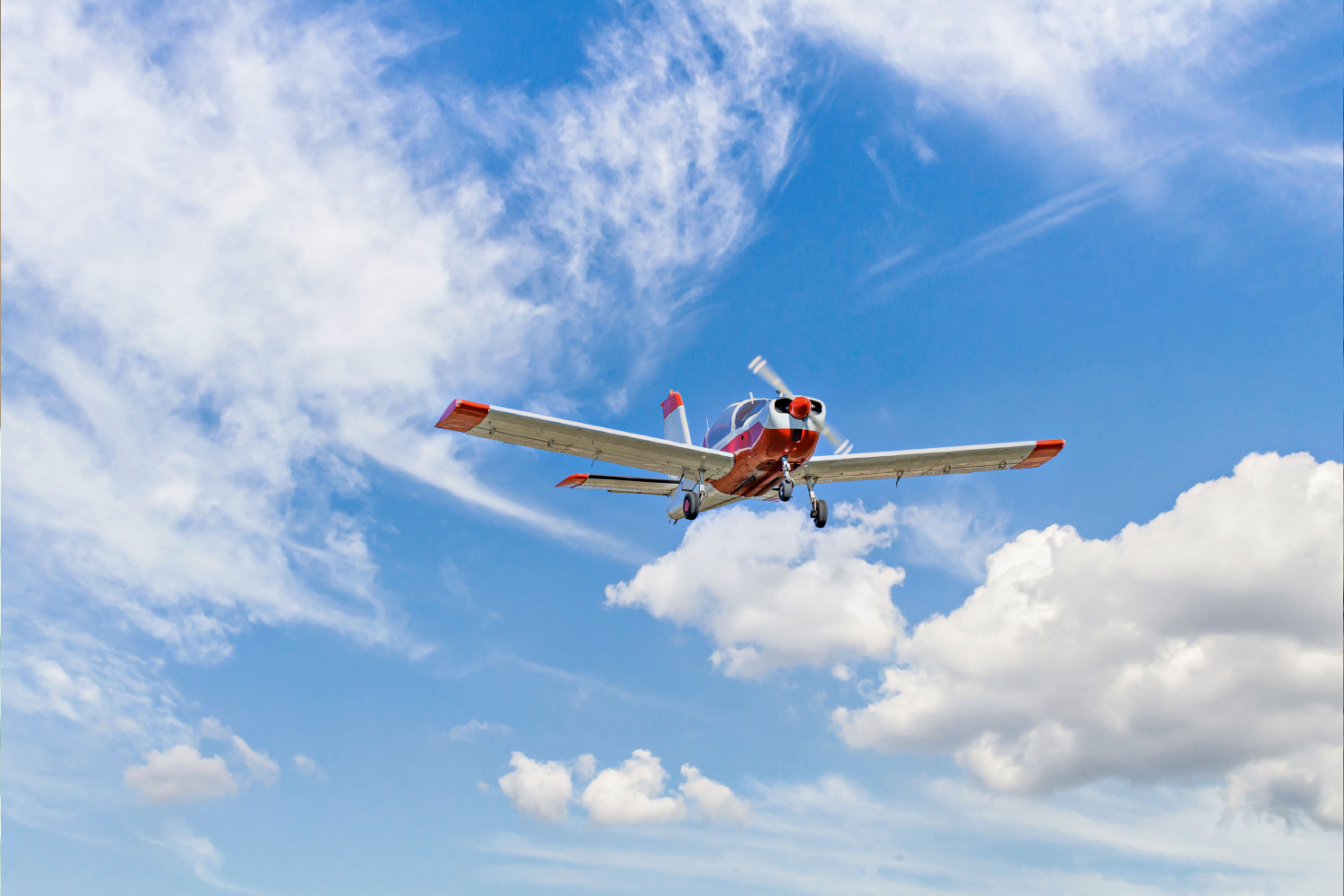 a-plane-is-flying-in-a-blue-sky-with-clouds-above